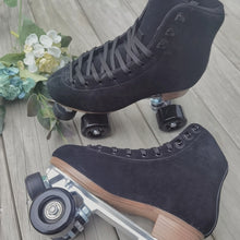 Load image into Gallery viewer, The Seed Project roller skates. colour is Black Robin with black laces on a wooden background surrounded by flowers and leaves.