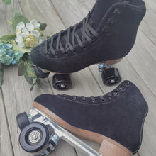Load image into Gallery viewer, The Seed Project roller skates. colour is Black Robin with black laces on a wooden background surrounded by flowers and leaves.
