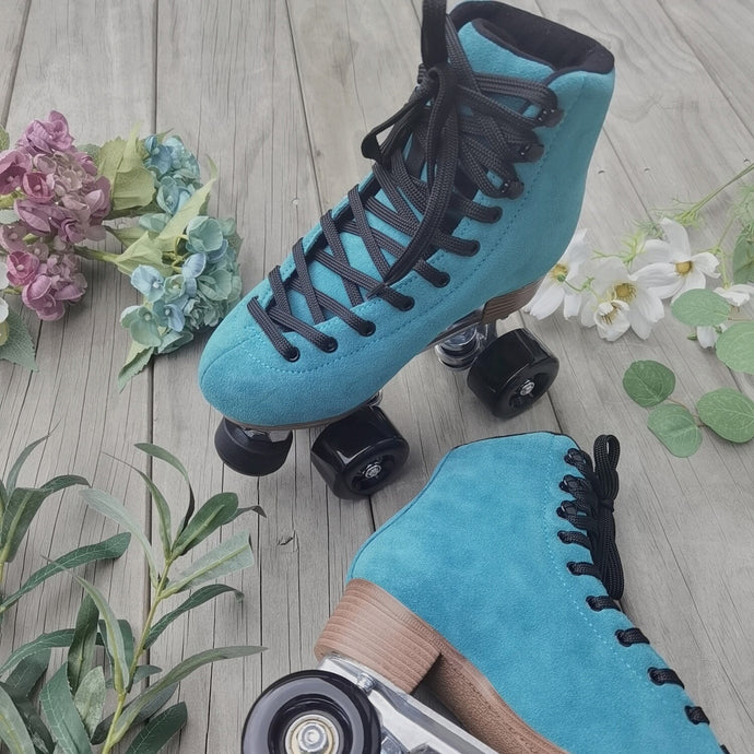 The Seed Project roller skates. Colour is Tui with black laces on a wooden background surrounded by flowers and leaves.