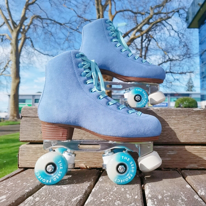 The Seed Project SeedPro* roller skates. colour is Aotearoa with light blue laces on wooden outdoor steps