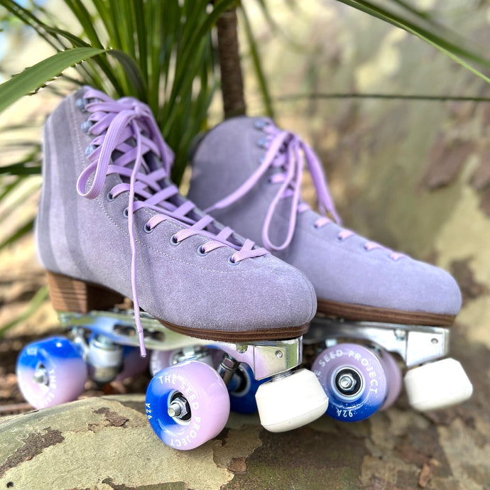 The Seed Project SeedPro* roller skates. colour is Tekapo with light purple laces sitting on a rock in fornt of plants