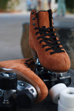 Load image into Gallery viewer, The Seed Project SeedPro* roller skates. Colour is Tieke with black laces sitting on a rock with an industrial blurred background
